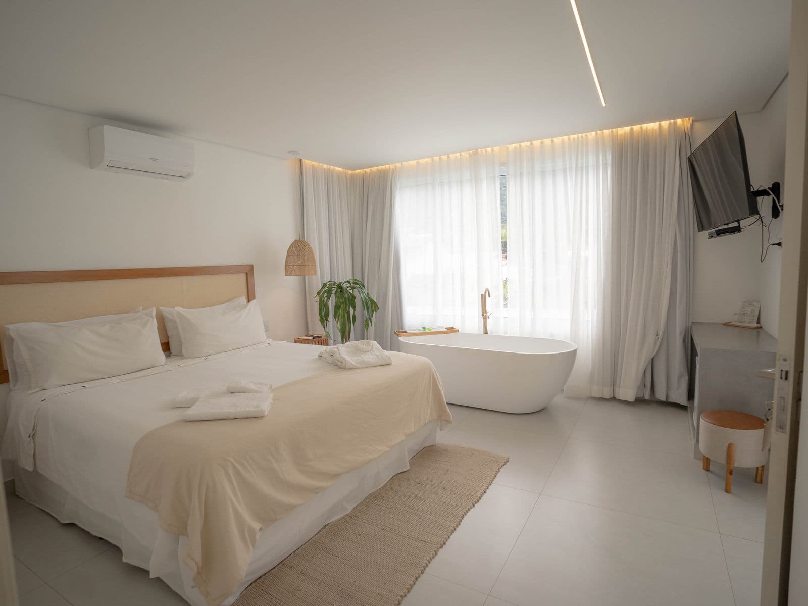 Suíte Master inteira: cama King, banheira de imersão junto à janela e a sanca de luz quente sobre as cortinas