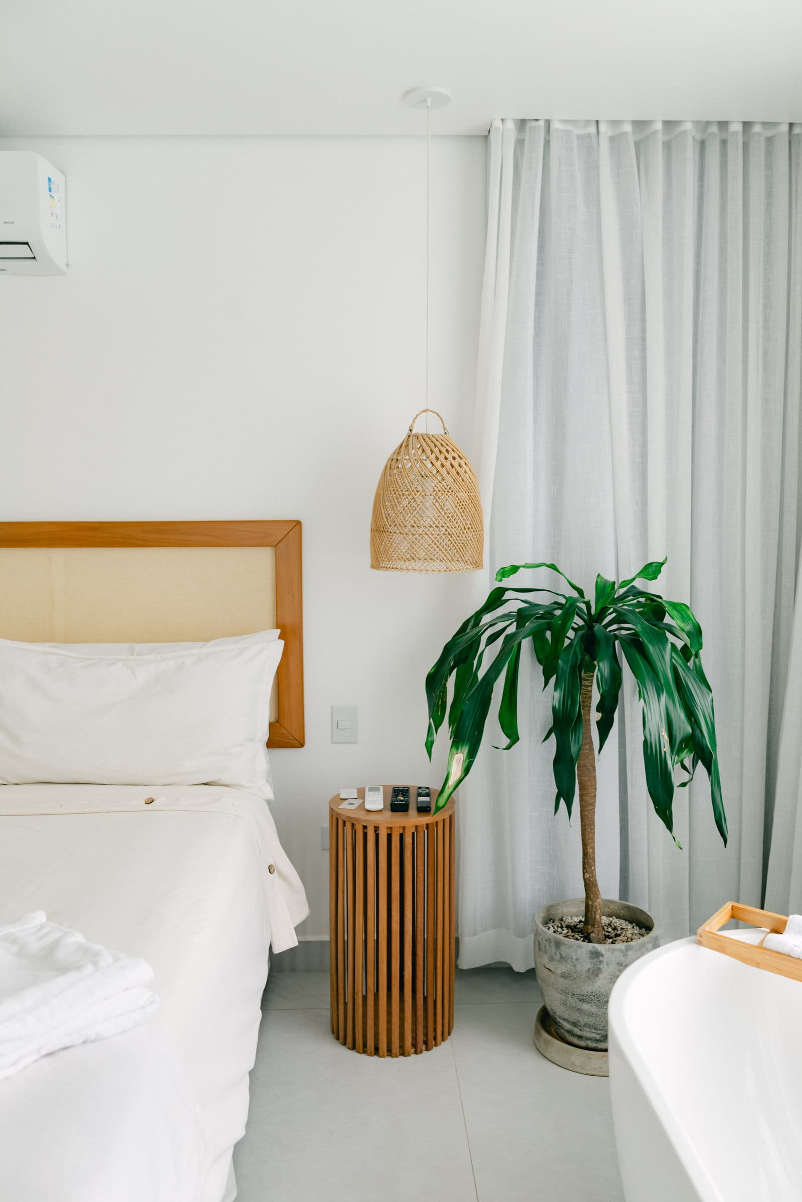 Suíte Master vista da cama, com a banheira à direita e a palmeira em vaso junto à cortina